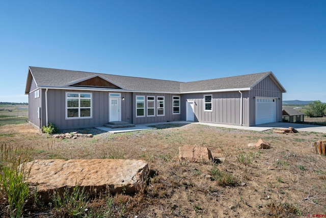 single story home featuring roof with shingles, board and batten siding, an attached garage, and driveway