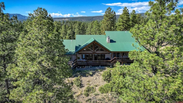 back of property with a forest view, metal roof, and a wooden deck