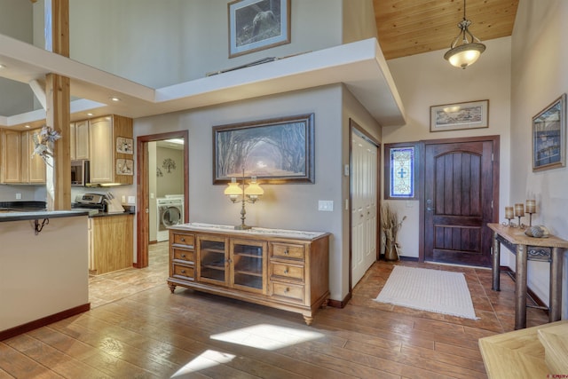 entrance foyer with washer / dryer, a towering ceiling, baseboards, and hardwood / wood-style flooring