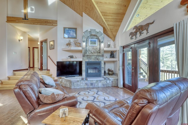 living area featuring high vaulted ceiling, a tile fireplace, wood finished floors, wood ceiling, and stairway