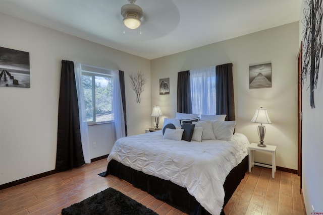 bedroom with ceiling fan, light wood-style flooring, and baseboards