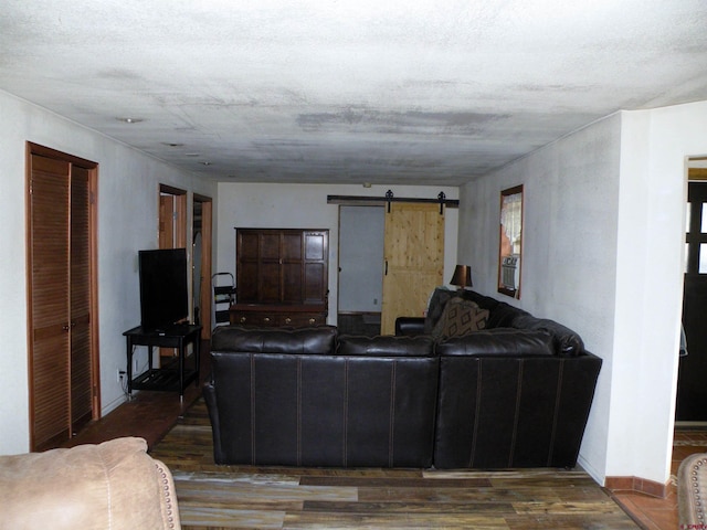 living area featuring a barn door, baseboards, and wood finished floors