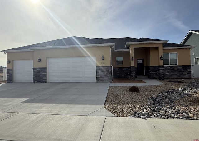 prairie-style house featuring a garage, stone siding, driveway, and stucco siding