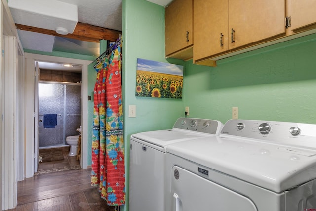 clothes washing area featuring dark wood-style floors, washer and clothes dryer, and cabinet space