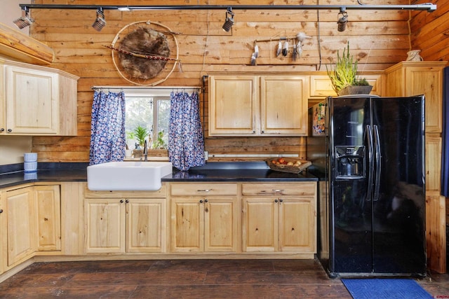 kitchen featuring dark countertops, dark wood-type flooring, black refrigerator with ice dispenser, light brown cabinets, and a sink