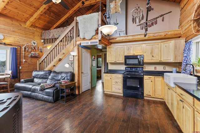 kitchen featuring dark countertops, wood walls, black appliances, high vaulted ceiling, and a sink