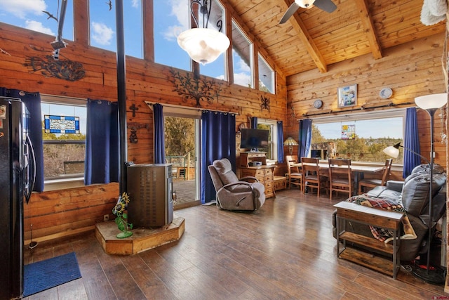 living room featuring vaulted ceiling with beams, ceiling fan, wooden ceiling, wooden walls, and wood-type flooring