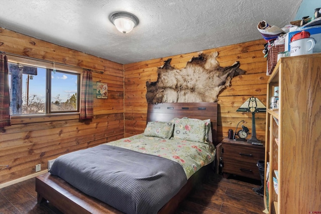 bedroom featuring wood walls, a textured ceiling, baseboards, and hardwood / wood-style floors