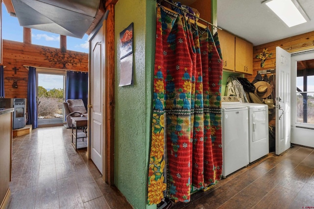 clothes washing area with washing machine and dryer, wooden walls, wood-type flooring, and a wealth of natural light