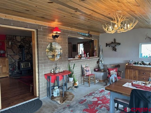 interior space with a wood stove, wooden ceiling, and an inviting chandelier