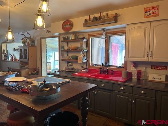 kitchen featuring open shelves, dark countertops, a sink, and white cabinetry