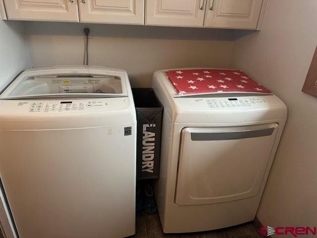 laundry room featuring dark wood-type flooring, cabinet space, and separate washer and dryer