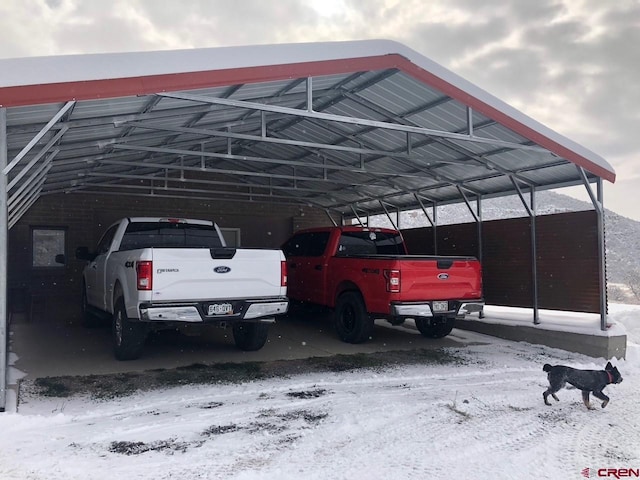 snow covered parking featuring a carport