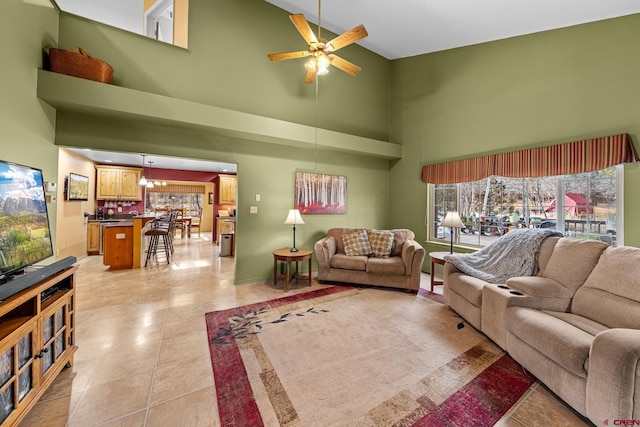 living area featuring light tile patterned floors, a towering ceiling, and a ceiling fan