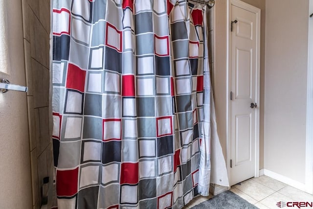 bathroom with curtained shower, tile patterned flooring, and baseboards