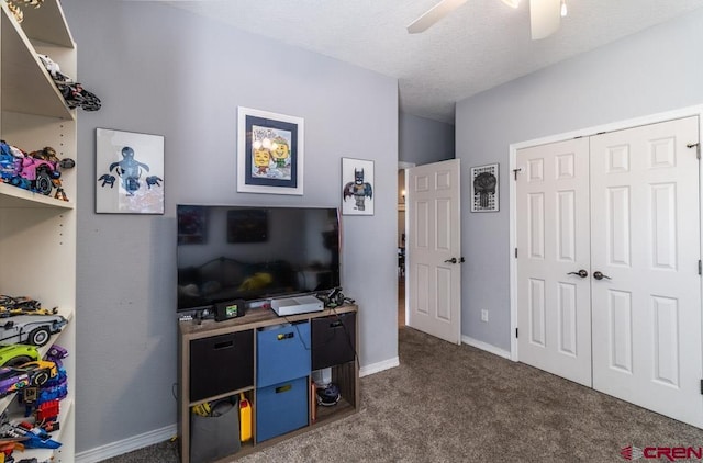 bedroom featuring baseboards, a ceiling fan, a textured ceiling, dark carpet, and a closet