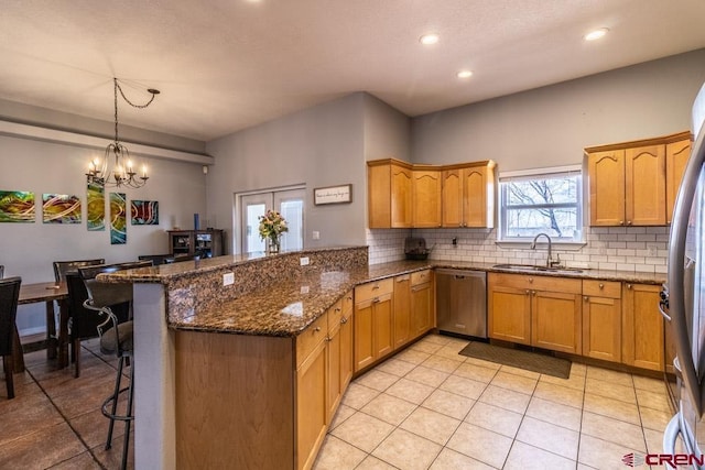 kitchen featuring a breakfast bar, backsplash, appliances with stainless steel finishes, a sink, and a peninsula