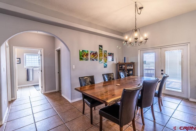 dining room with arched walkways, plenty of natural light, baseboards, and an inviting chandelier