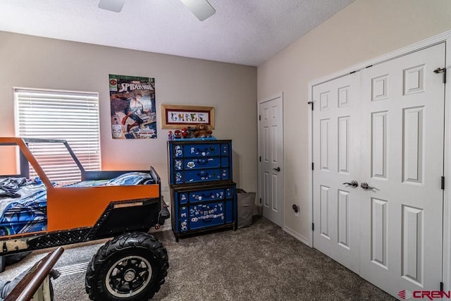 bedroom featuring a textured ceiling, carpet floors, a closet, and a ceiling fan