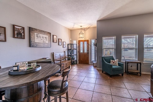 foyer entrance featuring a textured ceiling, baseboards, a wealth of natural light, and light tile patterned flooring