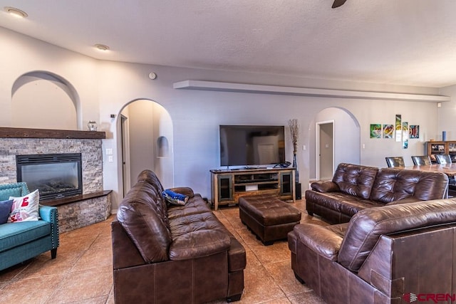 living area featuring a fireplace, arched walkways, and a textured ceiling