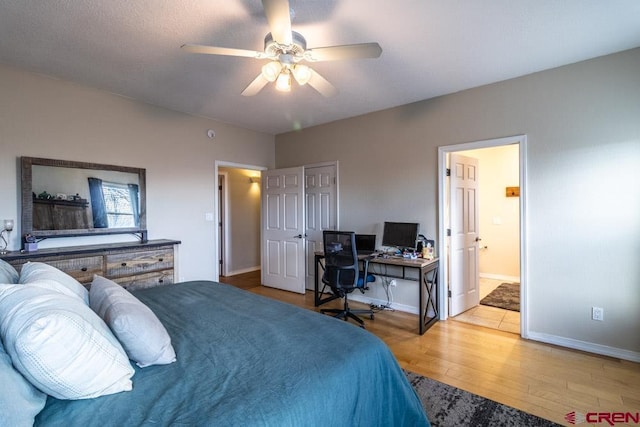 bedroom featuring ceiling fan, ensuite bath, baseboards, and wood finished floors