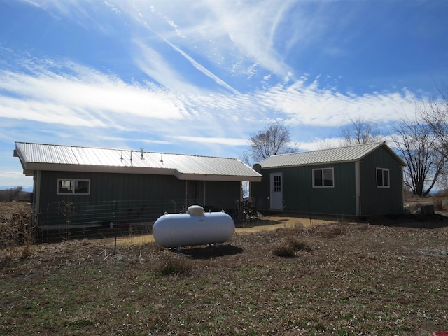 back of house featuring metal roof and an outdoor structure