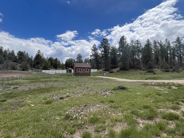 view of yard featuring a rural view, fence, and an outbuilding