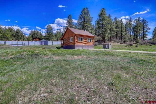 view of yard featuring a storage shed, fence, and an outdoor structure