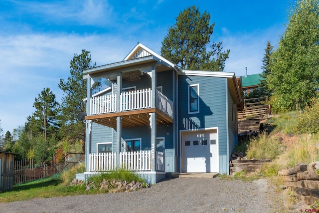 view of front of house featuring a garage, driveway, a porch, and a balcony