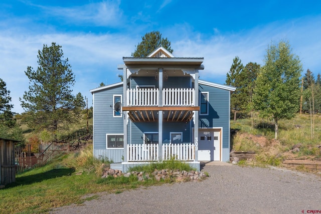 view of front of house with driveway, an attached garage, and a balcony