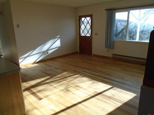 foyer featuring baseboard heating, wood finished floors, and baseboards