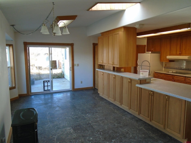 kitchen with black electric stovetop, freestanding refrigerator, a peninsula, under cabinet range hood, and baseboards