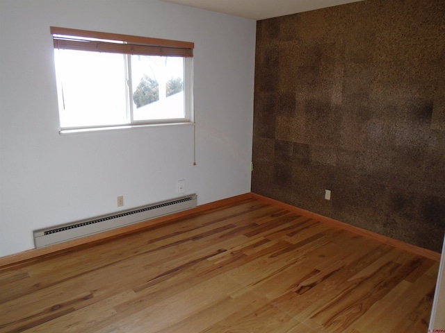 empty room featuring a baseboard radiator and wood finished floors