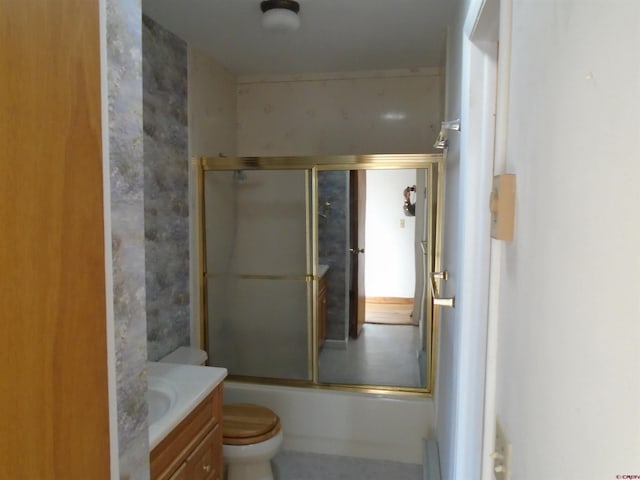 bathroom featuring toilet, bath / shower combo with glass door, and vanity