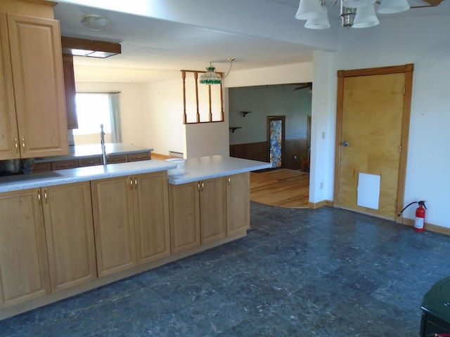 kitchen with light countertops, a sink, a peninsula, and light brown cabinetry