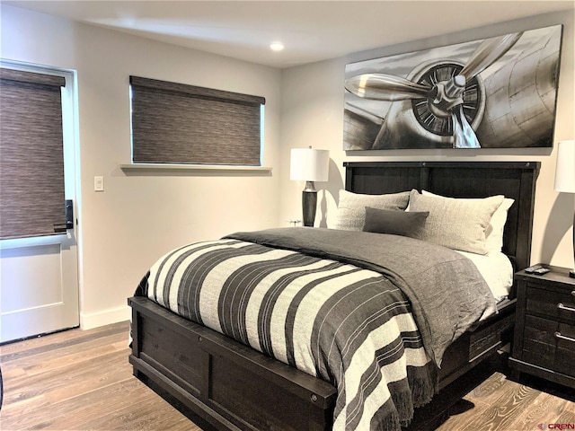 bedroom with baseboards, wood finished floors, and recessed lighting