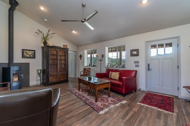 living room with baseboards, wood finished floors, a wood stove, and a ceiling fan