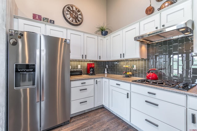 kitchen with under cabinet range hood, gas stovetop, white cabinets, stainless steel fridge with ice dispenser, and tasteful backsplash