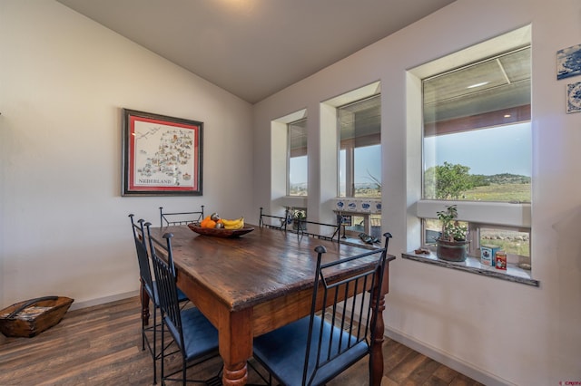 dining area with dark wood-type flooring, lofted ceiling, and baseboards