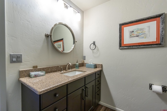 bathroom featuring a textured wall, wood finished floors, vanity, and baseboards