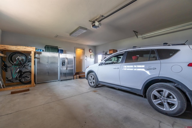 garage with stainless steel fridge and a garage door opener