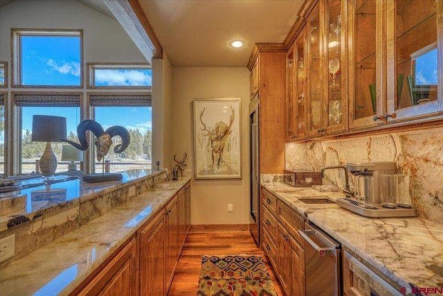 bar featuring tasteful backsplash, wood finished floors, a sink, stainless steel dishwasher, and recessed lighting