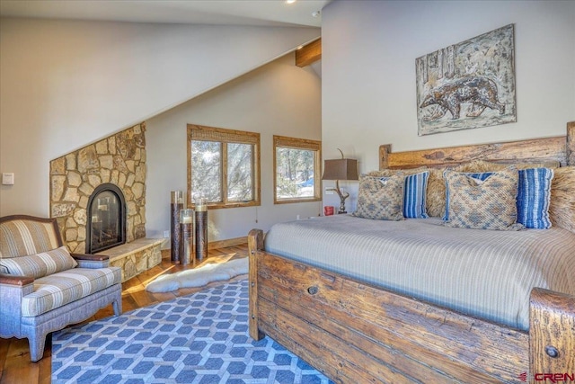 bedroom with high vaulted ceiling, a fireplace, beamed ceiling, and wood finished floors