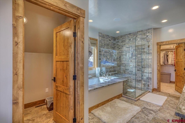 bathroom featuring a walk in closet, recessed lighting, a shower stall, baseboards, and a bath