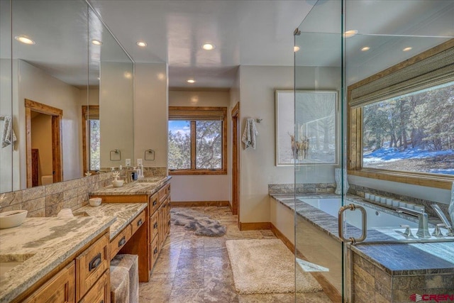 full bathroom featuring a bath, recessed lighting, baseboards, and double vanity