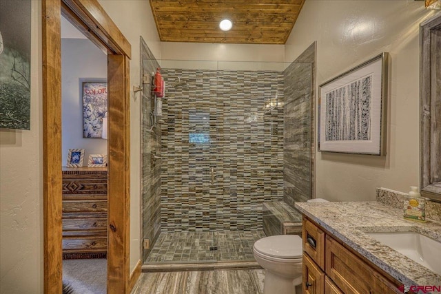 bathroom featuring toilet, wood ceiling, a tile shower, and vanity