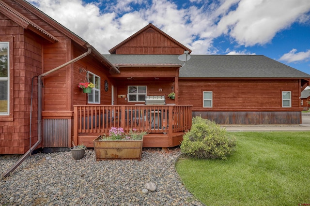 back of house with a shingled roof and a lawn