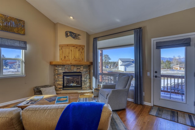 living room featuring a fireplace, baseboards, vaulted ceiling, and wood finished floors