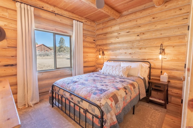 bedroom with log walls, beam ceiling, wood finished floors, and wood ceiling